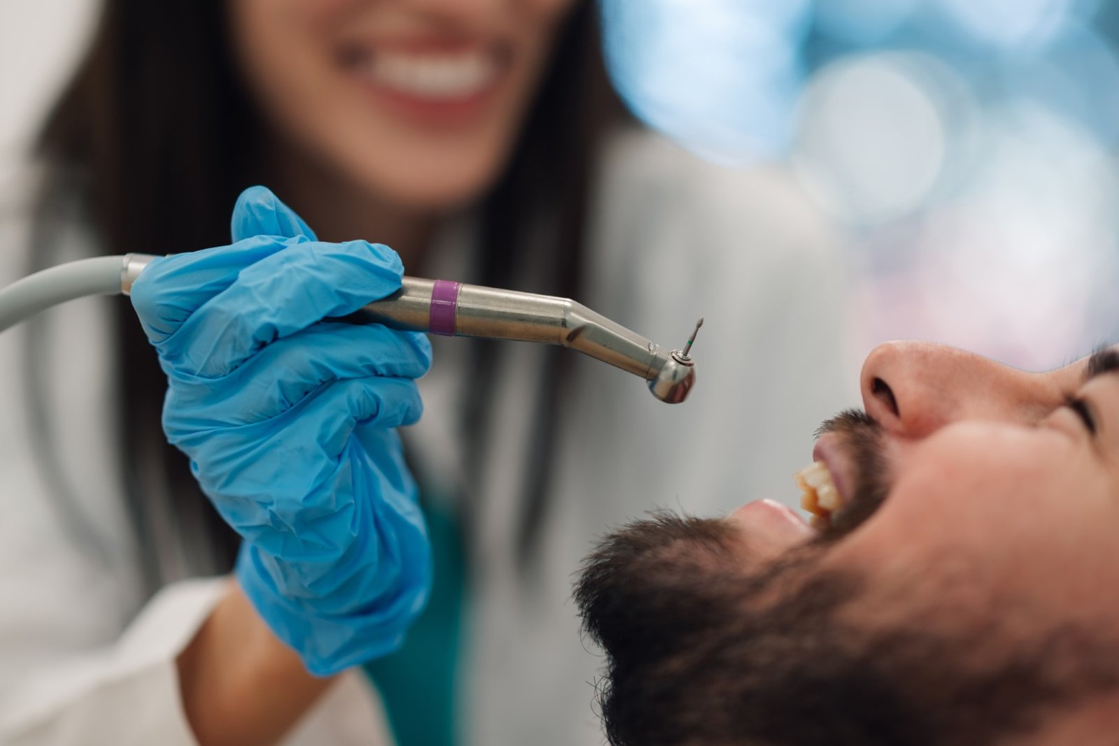 Dentist using dental drill on patient's teeth during checkup