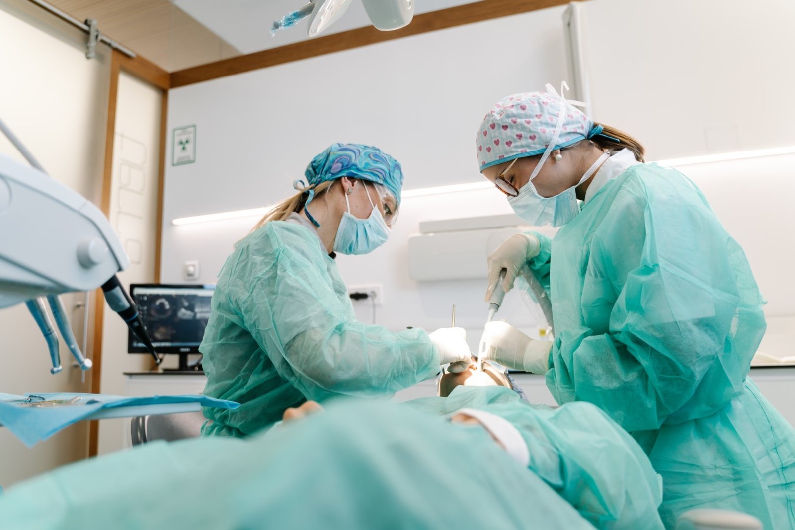 professional dentists in latex gloves using clean tools to perform oral procedure on unrecognizable patient in contemporary clinic.